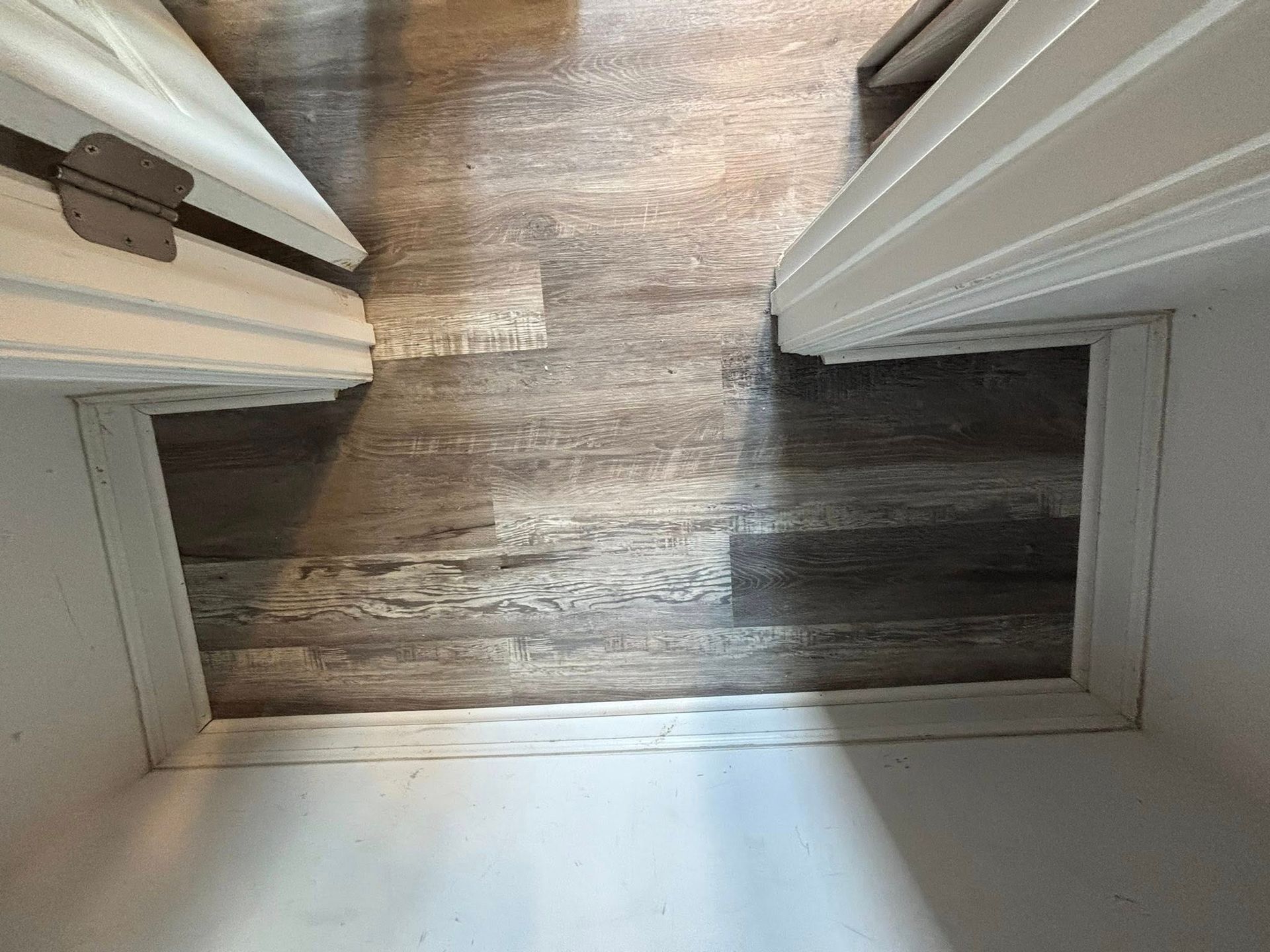 Looking down at a doorway threshold with white trim and wood flooring beyond