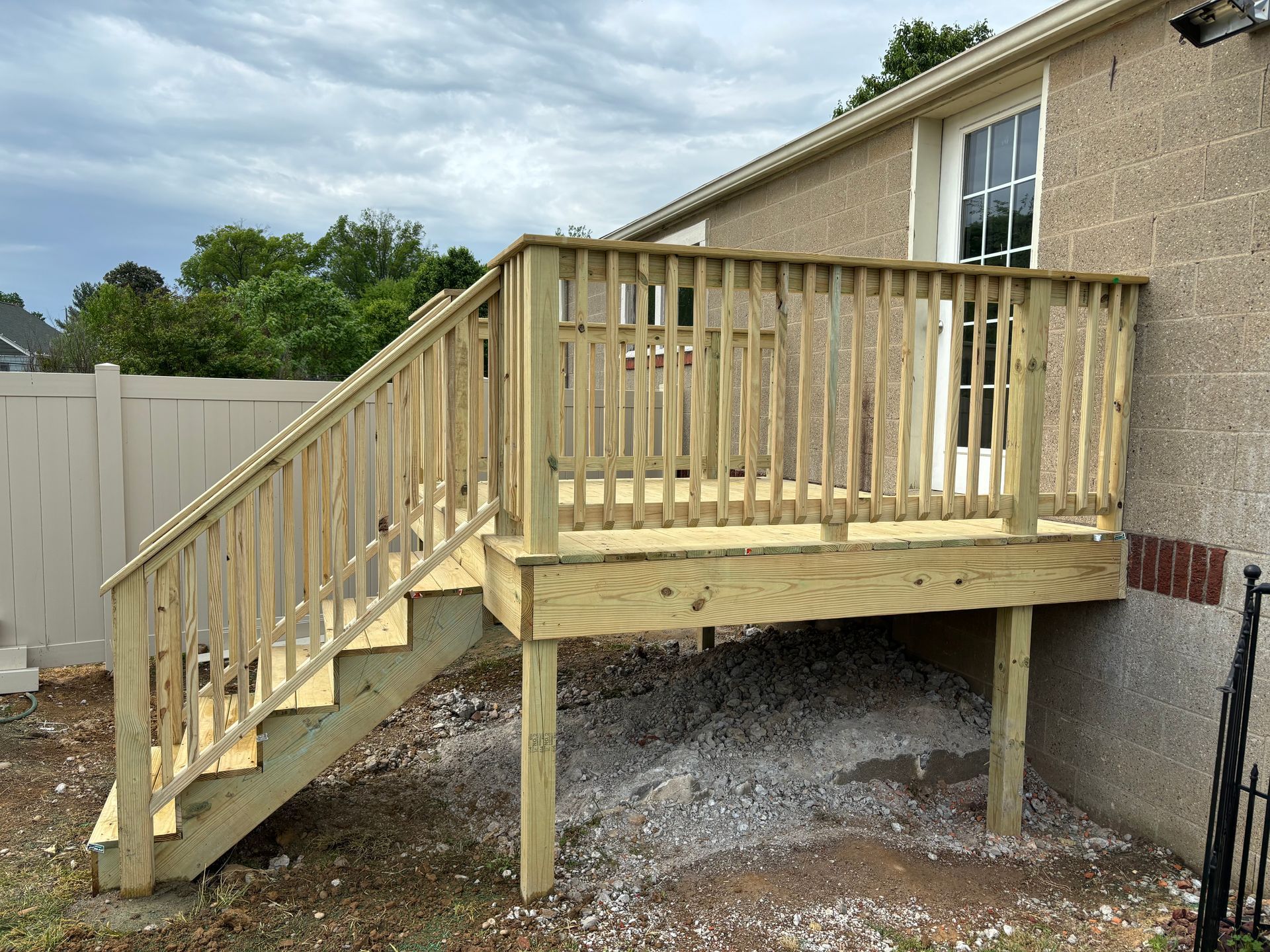 Wooden backyard deck stairs and railing beside a beige house