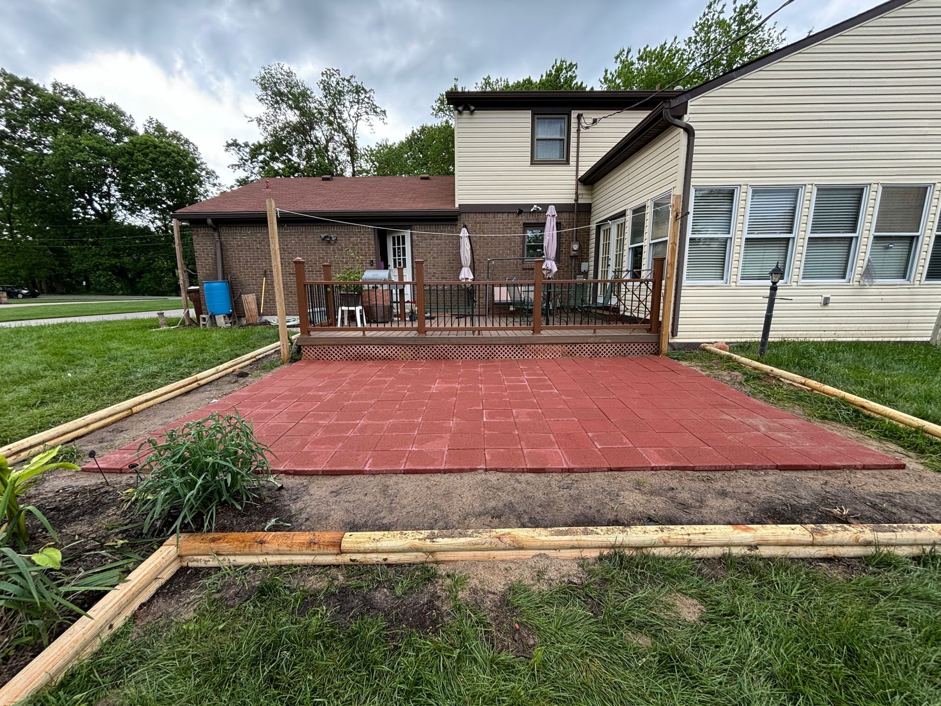 Backyard deck with red patio and ramp beside a house and garden beds