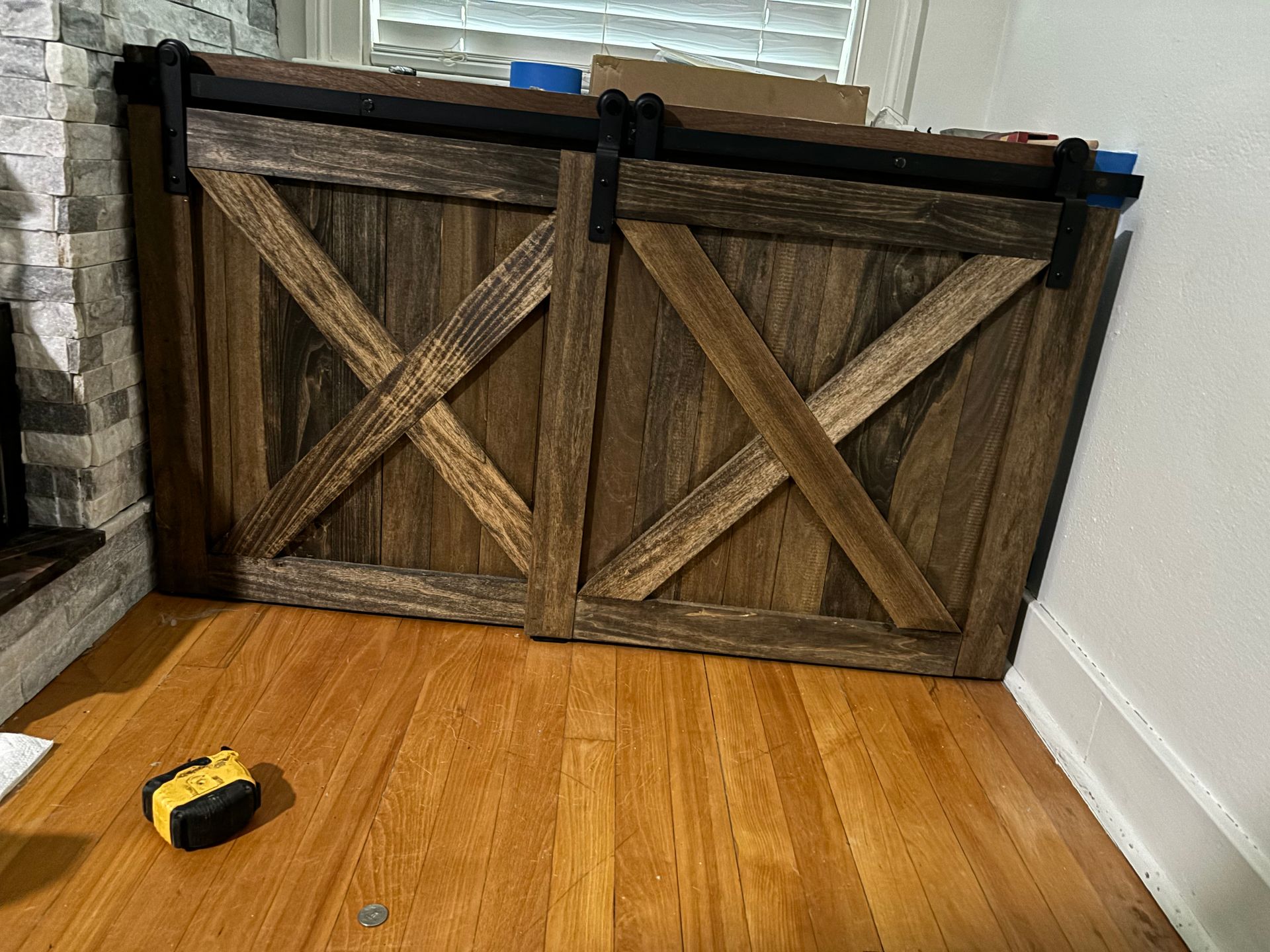 Two rustic wooden barn-style doors blocking a doorway, with a toy truck on a hardwood floor.