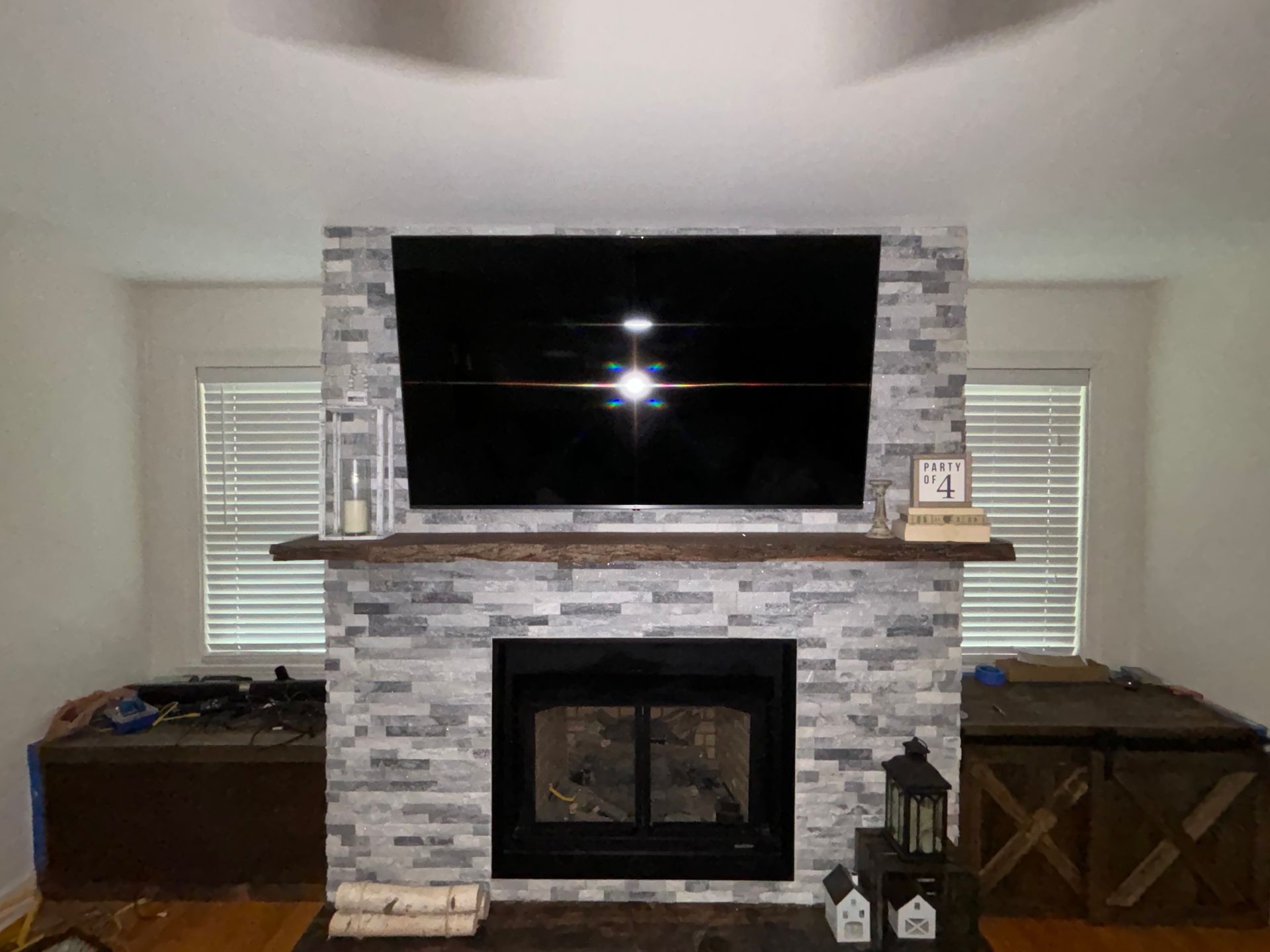 Living room fireplace with mounted TV, stone surround, and wooden side tables