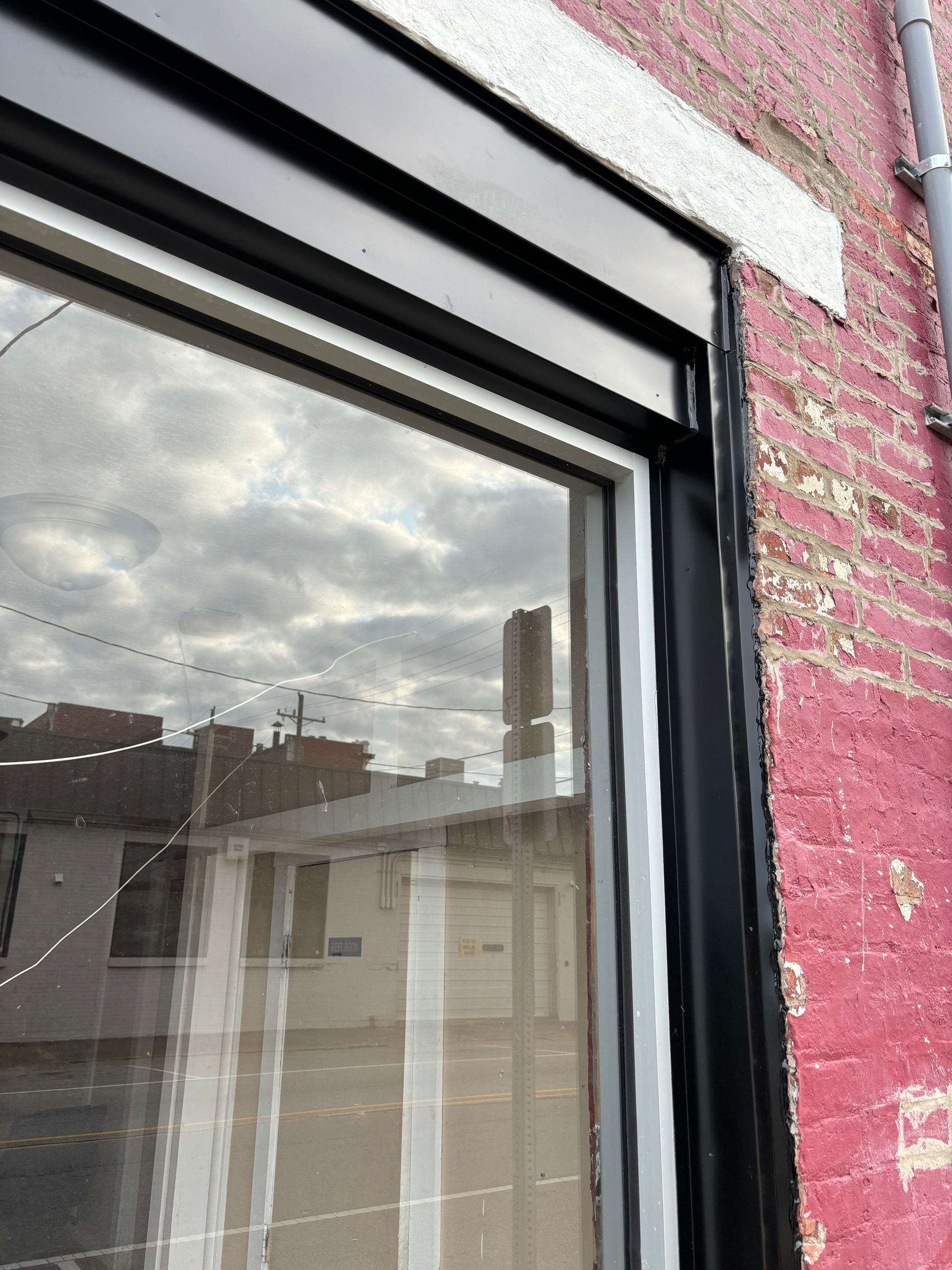 Rainy city view reflected in a window beside a pink brick wall