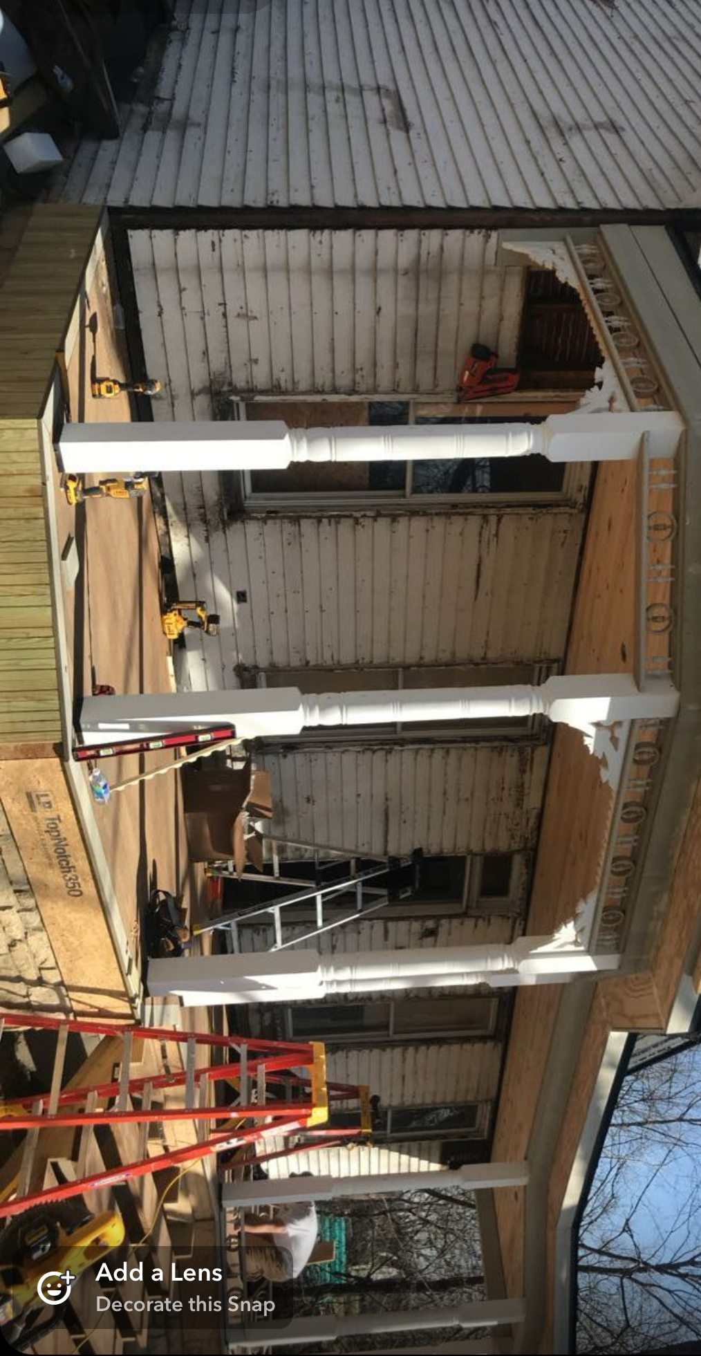 Dilapidated porch with missing walls, exposed beams, and a red ladder inside a damaged house.