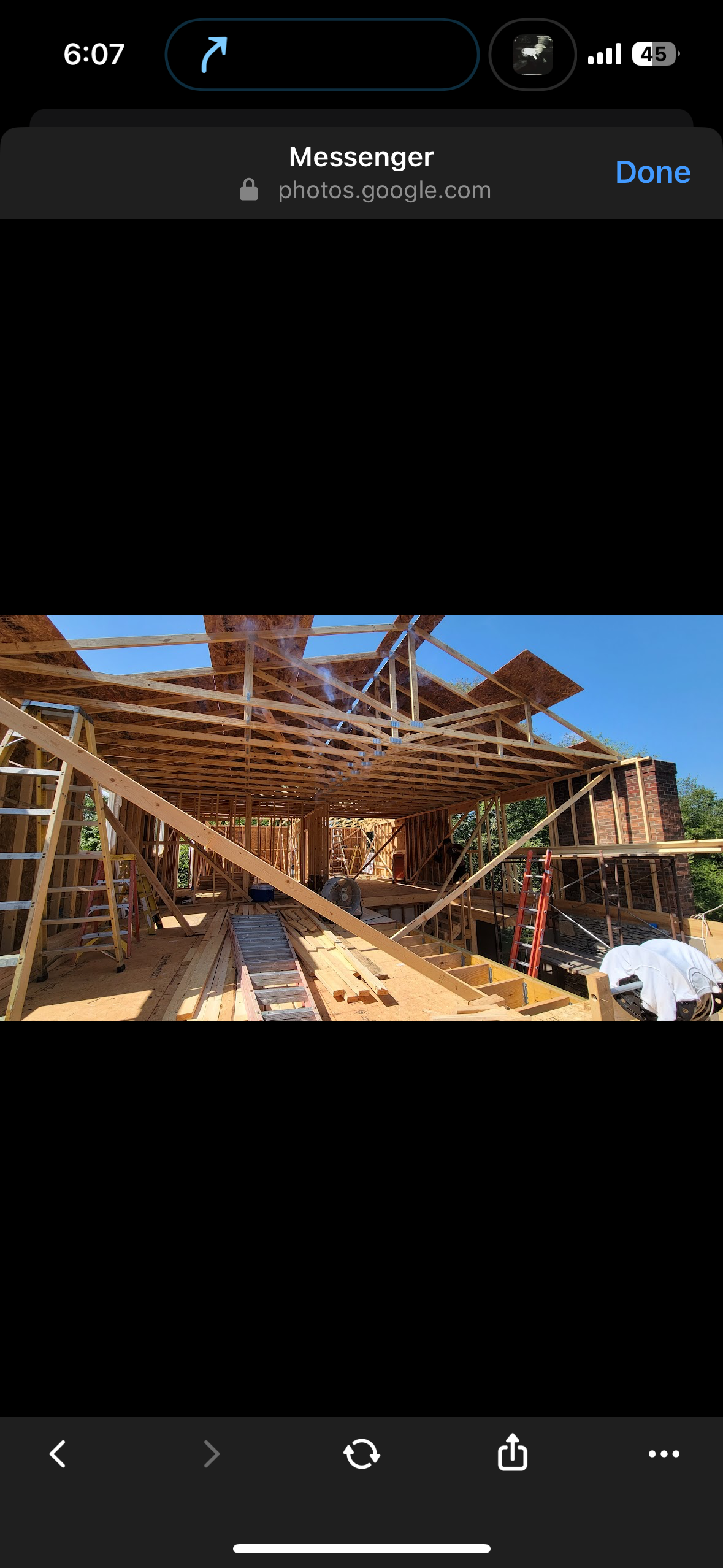 Partially built wooden structure with scaffolding and stairs under a clear blue sky