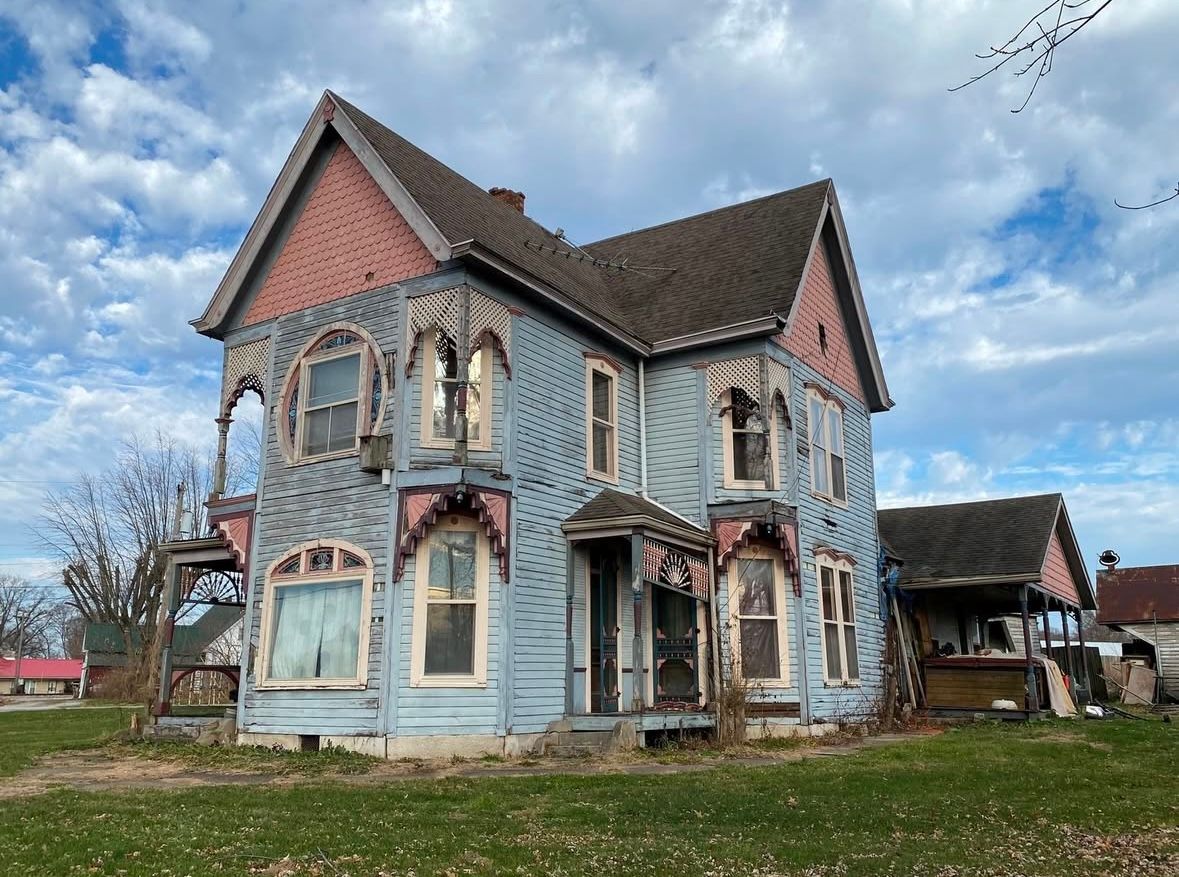 Blue Victorian house with ornate trim and gabled roof in a grassy yard