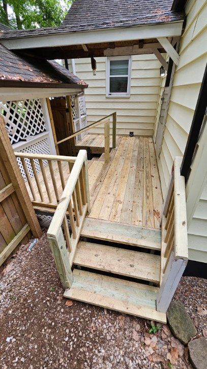 Wooden ramp and short steps leading to a house entryway with railings and tan siding