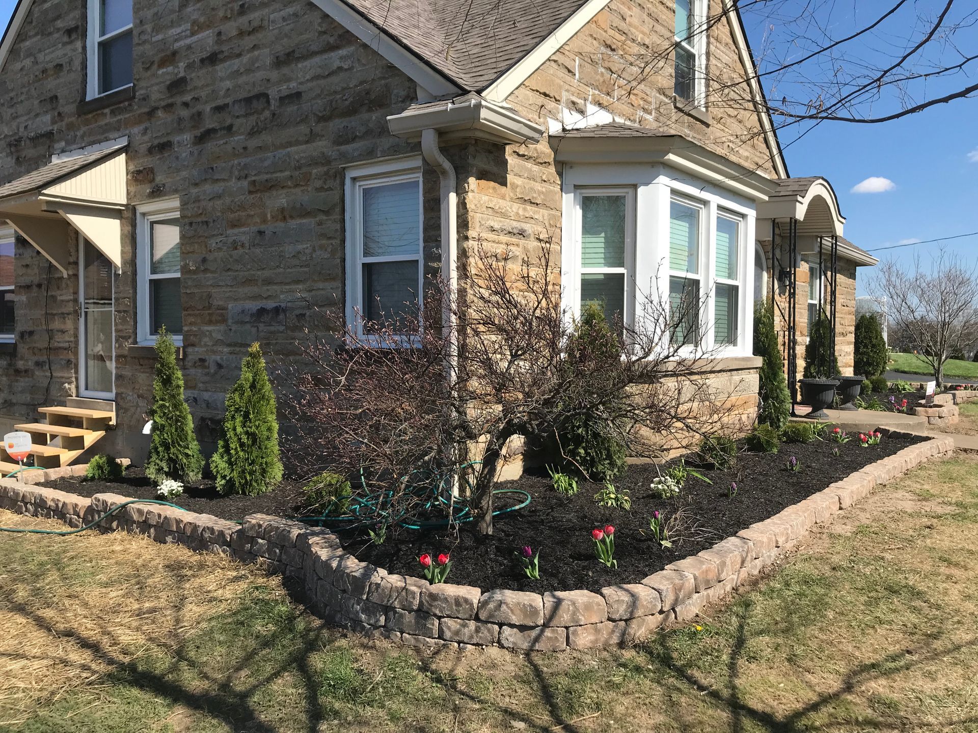 Stone house with a bay window and landscaped front garden along a walkway
