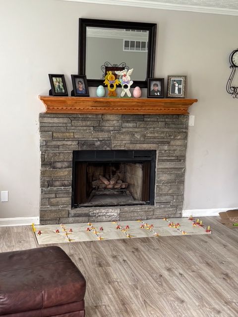 Living room stone fireplace with mantle, mirror, framed photos, and teddy bear decor