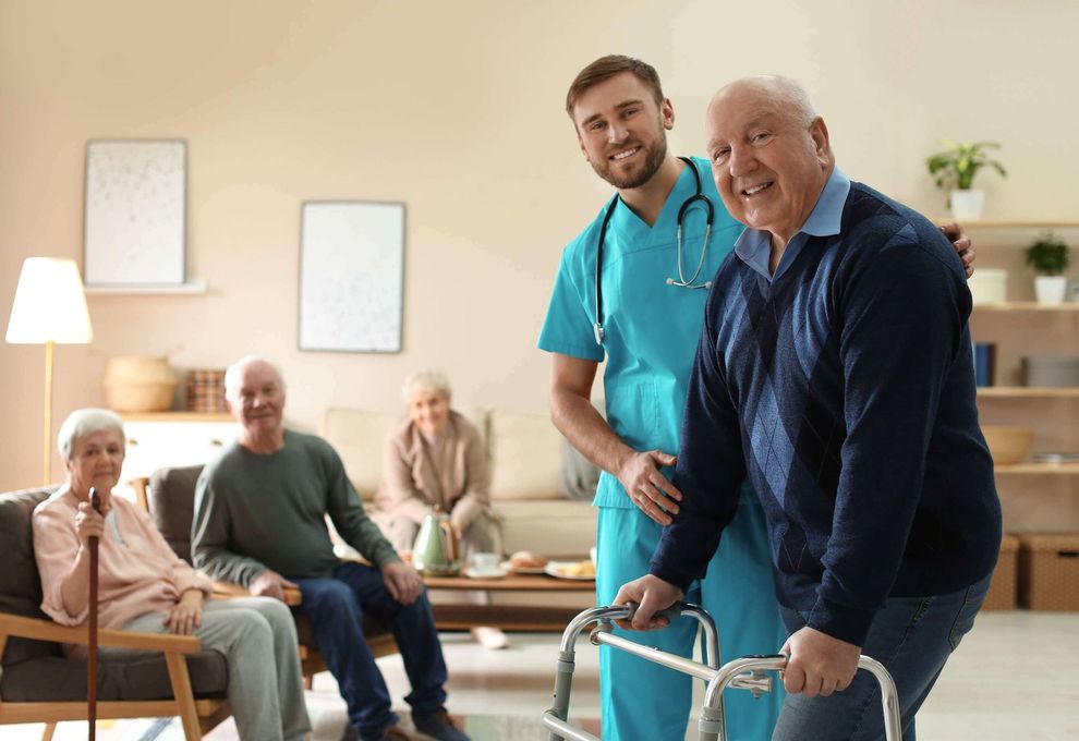 Caregiver assisting a smiling man with a walker in a bright senior living room