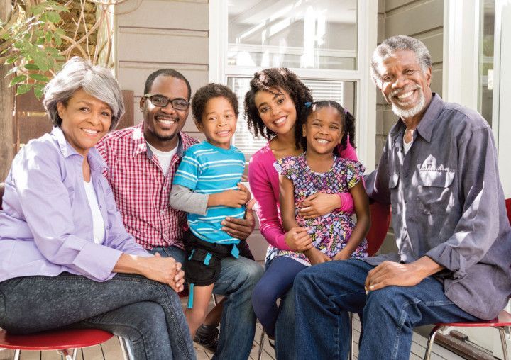 Family sitting together on a couch, smiling in a bright living room.