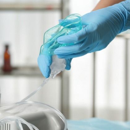 Gloved hands cleaning medical tubing with a blue wipe