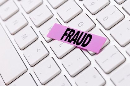 Pink “FRAUD” tag on a white computer keyboard