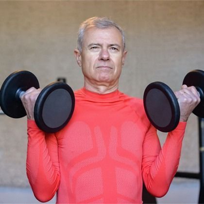 Man in red shirt doing dumbbell curls indoors