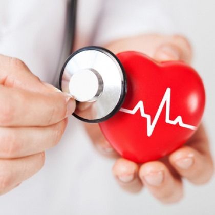 Doctor’s hand holding a stethoscope to a red heart with an ECG line symbol