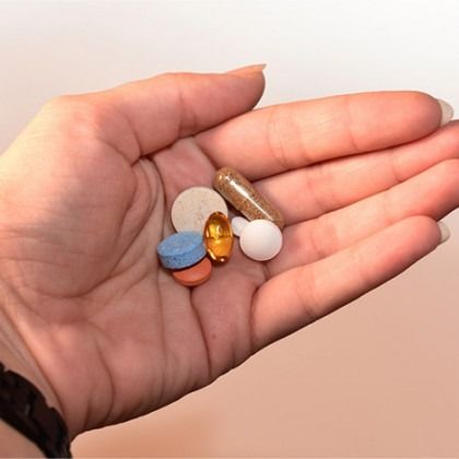 Open hand holding several colorful pills and capsules