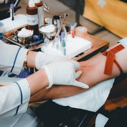 Healthcare worker taking blood from a patient’s arm with a syringe in a clinic setting