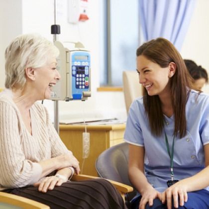 Nurse smiling and talking with a patient in a hospital room