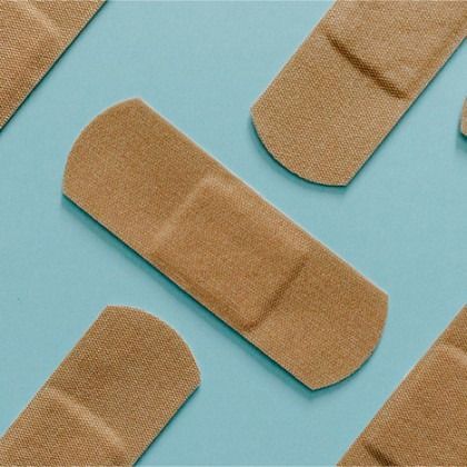 Several beige adhesive bandages scattered on a light blue background