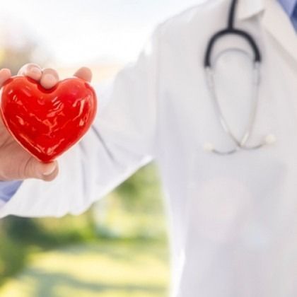 Doctor holding a red heart-shaped object with a stethoscope around the neck