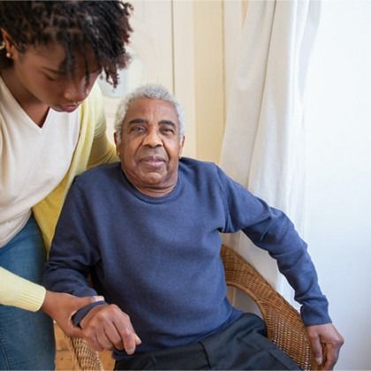 Two people sitting together indoors, one gently holding the other’s hand