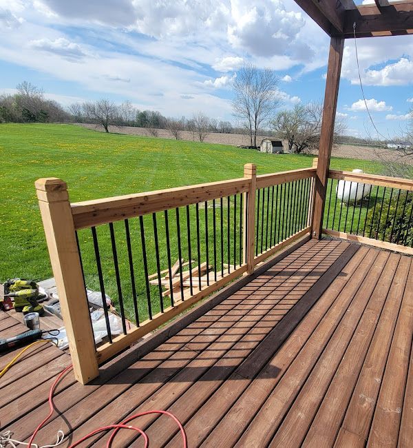 A wooden deck with a metal railing and a lawn in the background