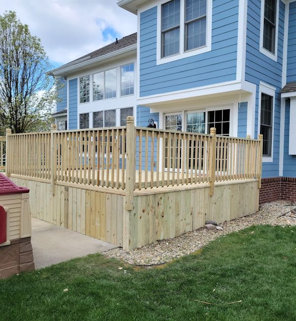 A blue house with a wooden deck in front of it.