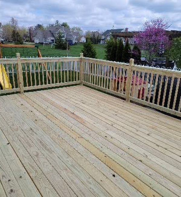 A wooden deck with a wooden railing and a swing set.