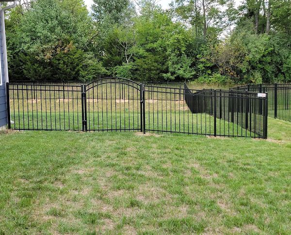 A black metal fence surrounds a lush green yard.