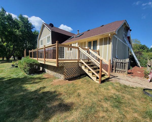 A house with a wooden deck and stairs in front of it.