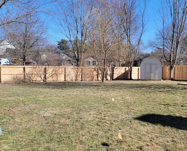 A backyard with a wooden fence and a garage.