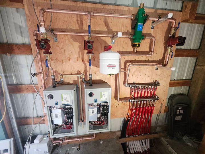 Copper pipe and HVAC components mounted on plywood, including pumps, valves, and a distribution manifold.