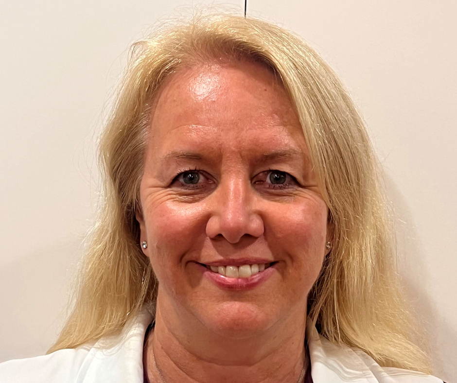Woman in white collared shirt smiling against a plain background, with “40” embroidered on the chest.