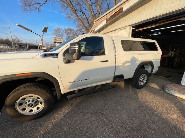 White pickup truck with a camper shell parked outside a building with a partially open garage door.