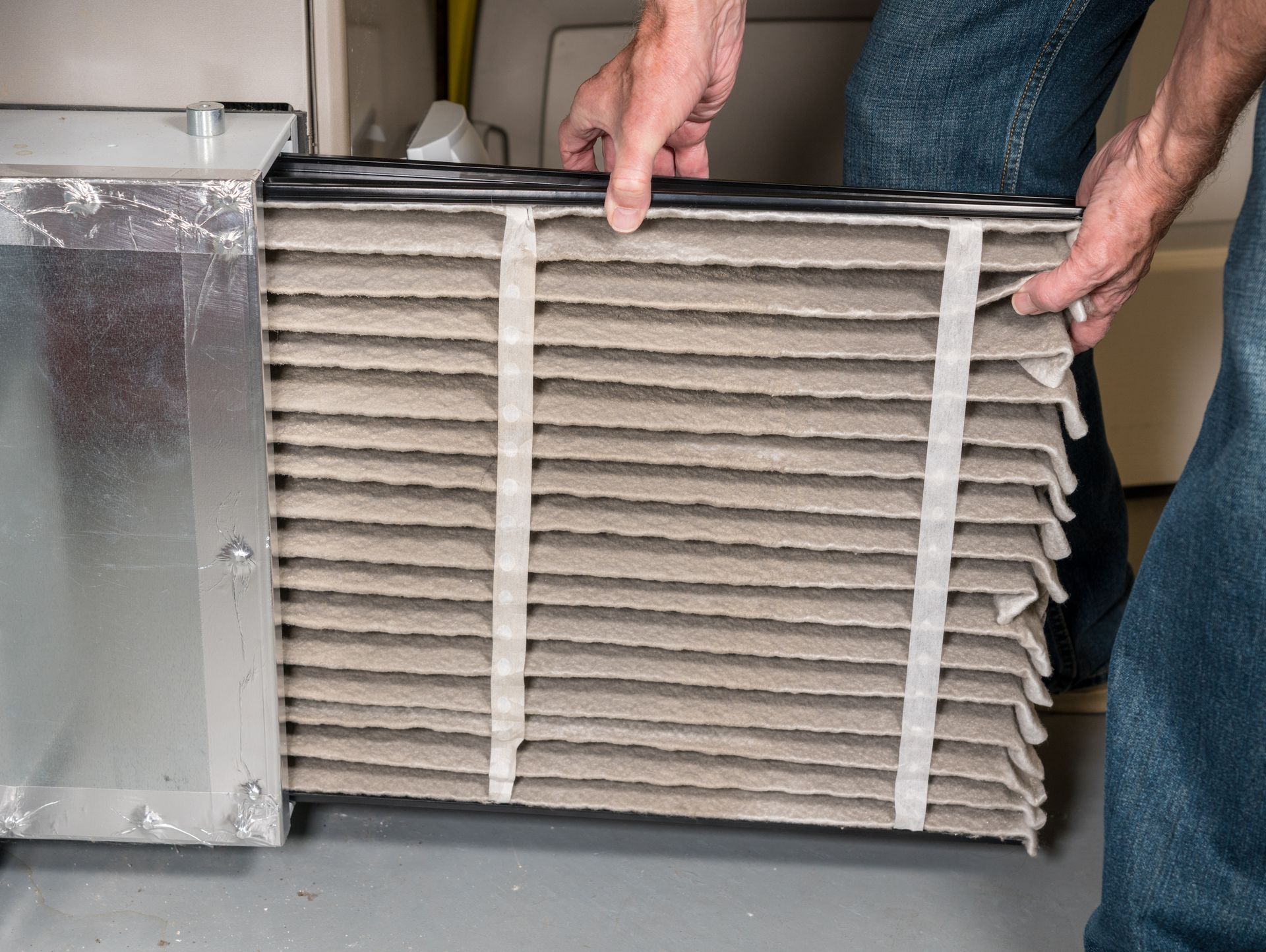 A man replaces his HVAC filter, completing DIY HVAC maintenance.
