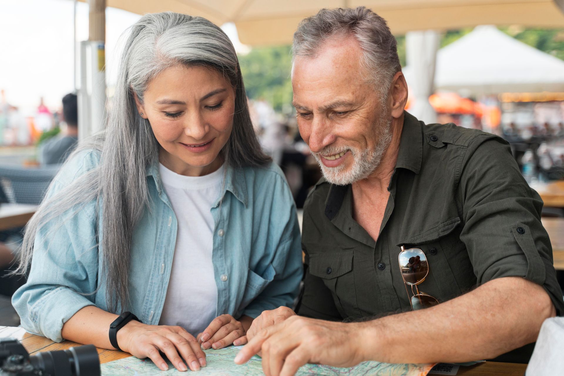 Two people reviewing documents together at an outdoor café, leaning over a table with focused expressions