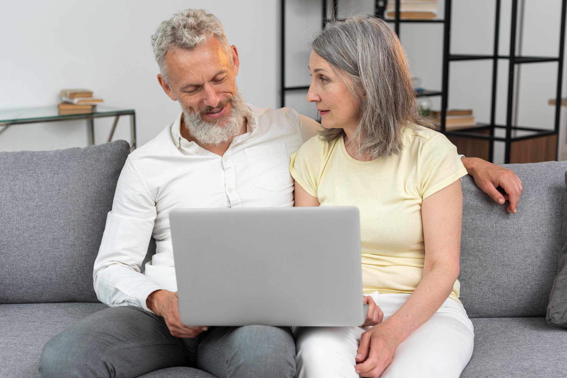 Couple on a gray couch using a laptop and looking at the screen together