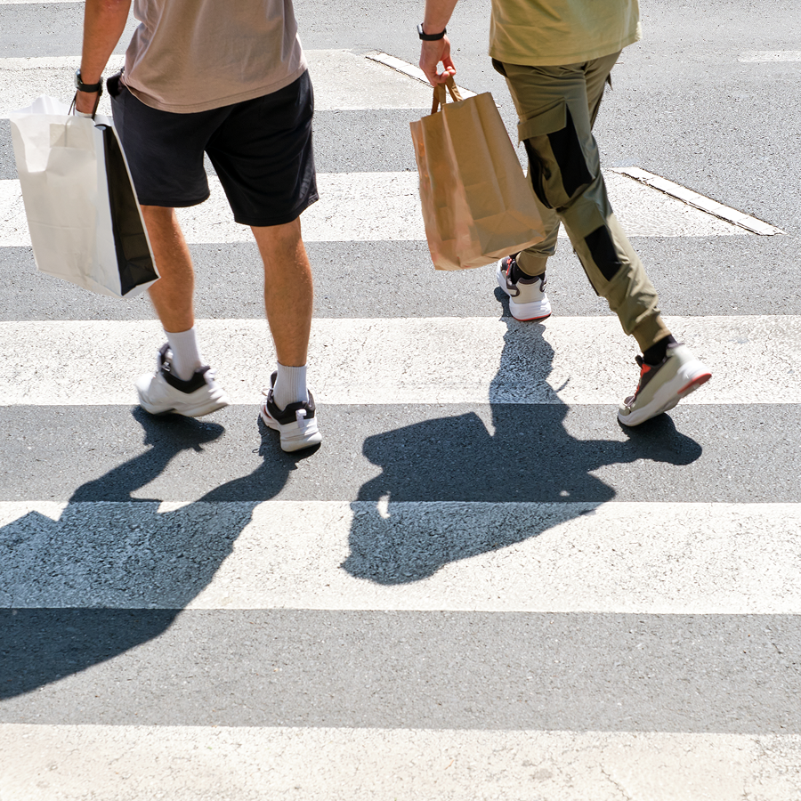 Two people crossing a street with bags in their hands