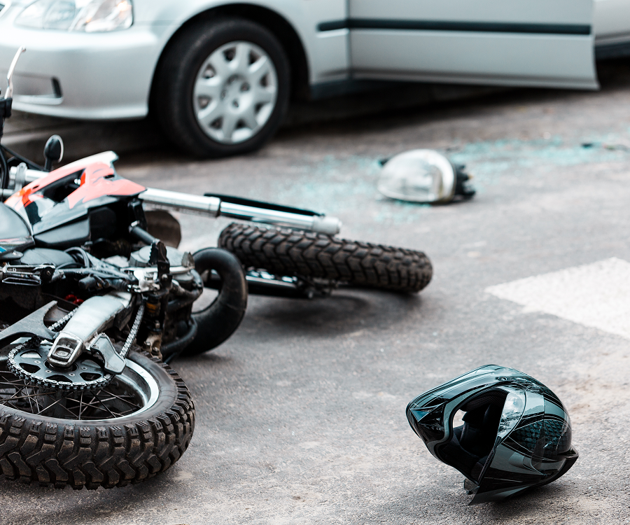 A motorcycle has crashed into a car on the side of the road.