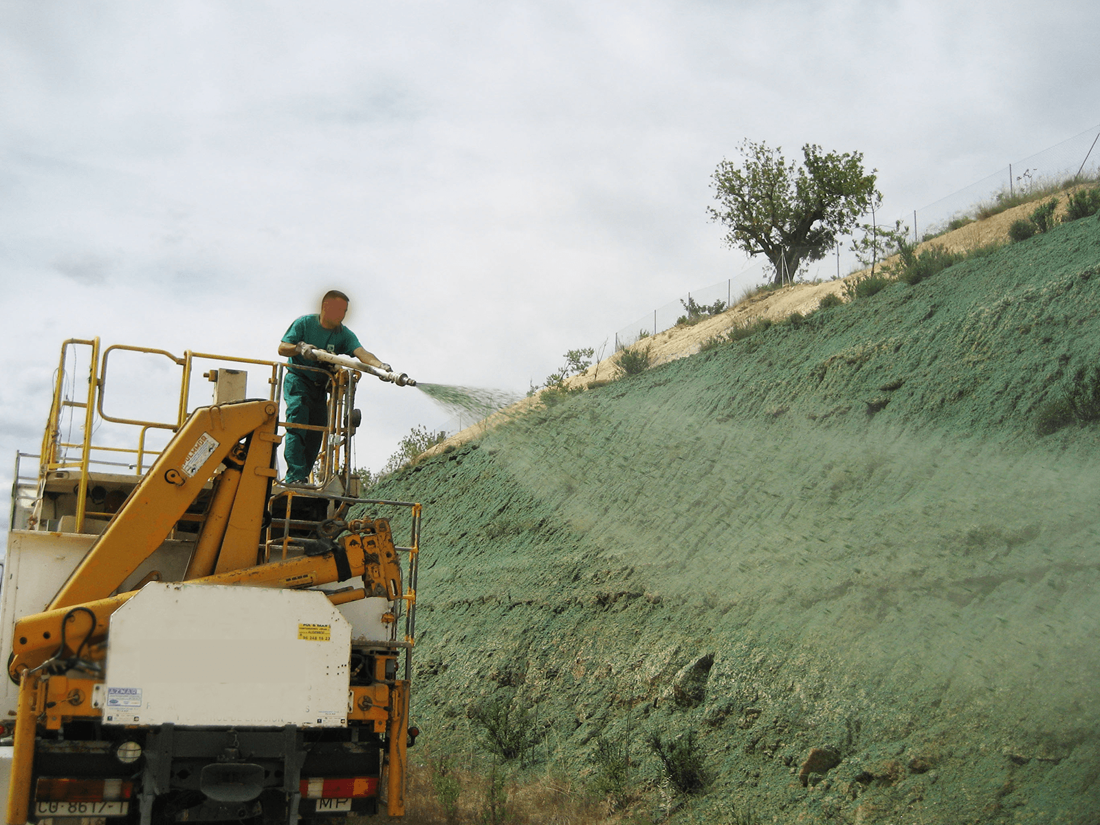 Un uomo che spruzza una collina con un tubo da una gru