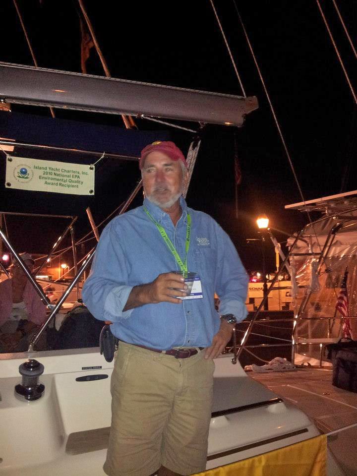 A man in a blue shirt is standing on a boat at night