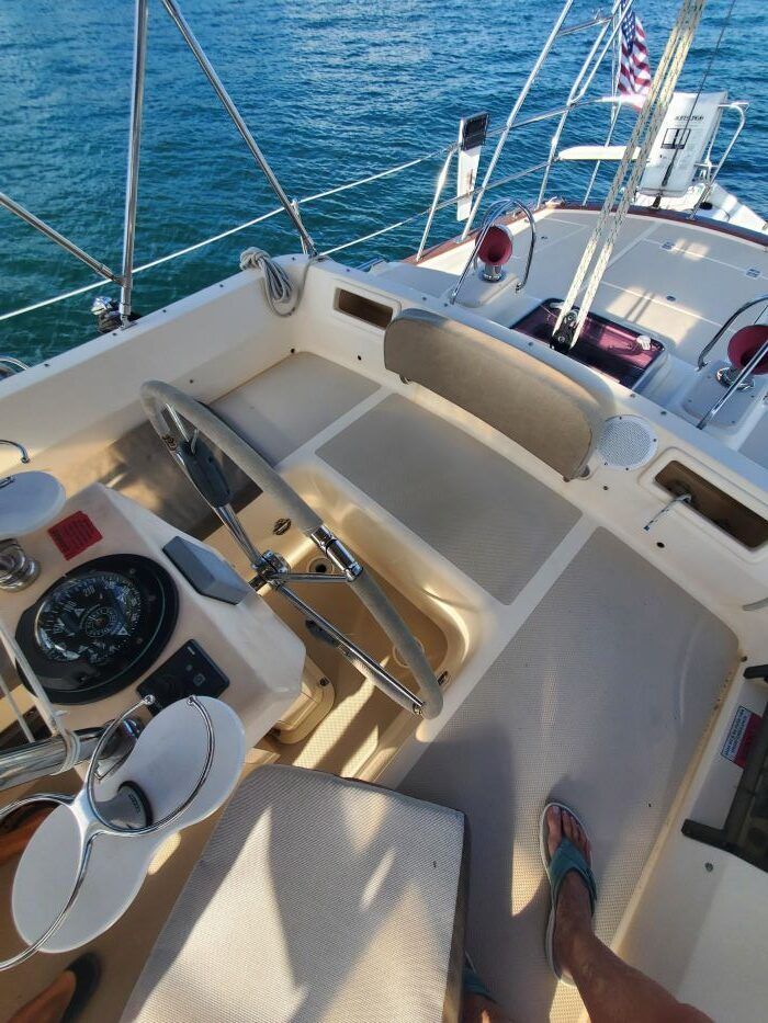 A person is standing on the deck of a sailboat in the ocean.