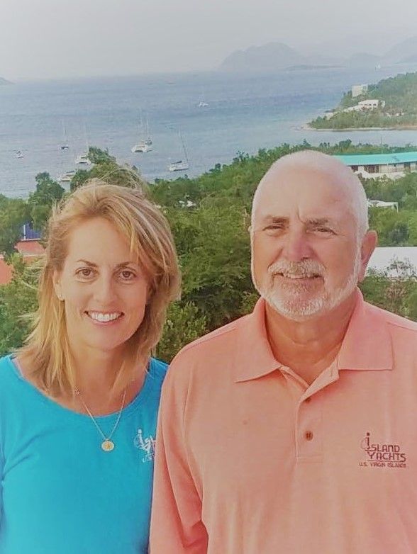 A man and a woman are standing next to each other in front of a body of water.