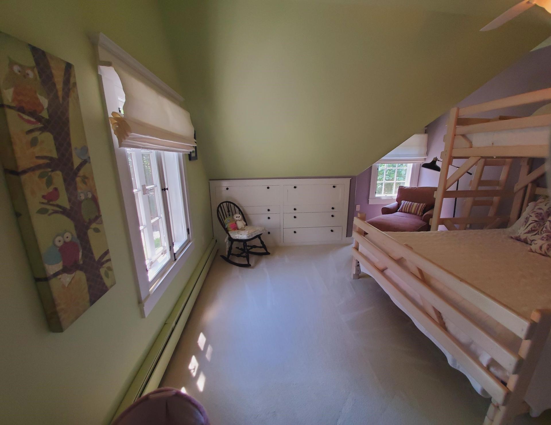 Bedroom with bunk bed, rocking chair, and owl artwork; light green walls, window.