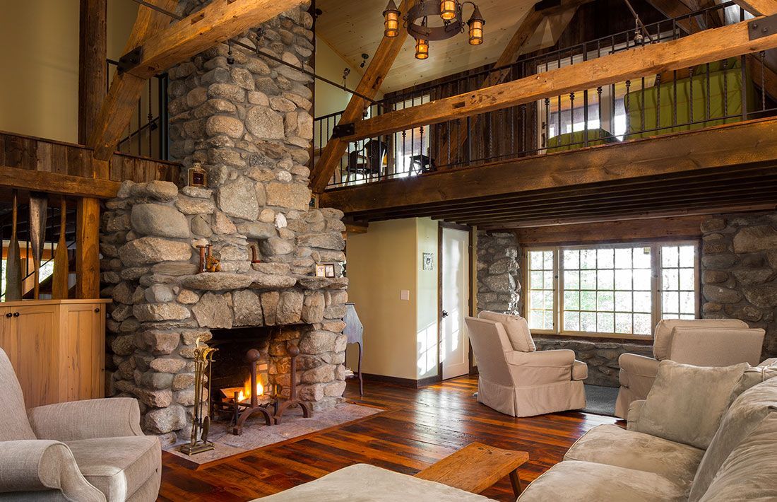 A living room with a stone fireplace and lots of furniture.
