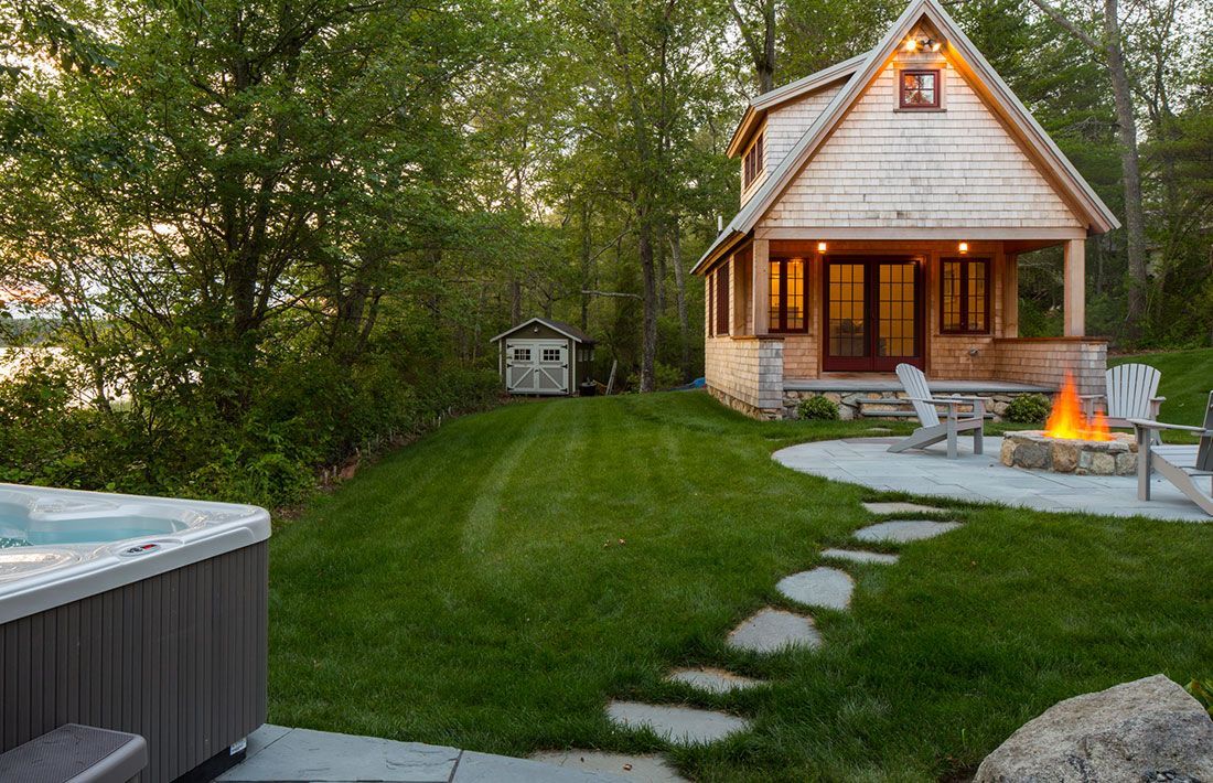A small house with a hot tub and a fire pit in front of it.