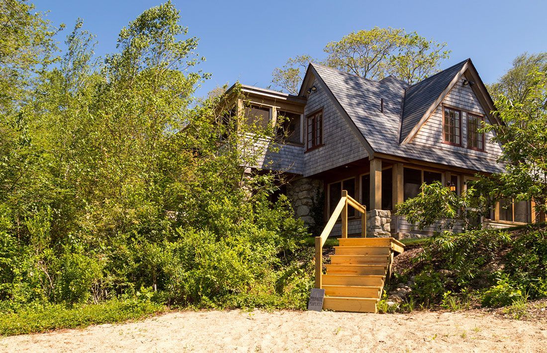 A house with stairs leading up to it is surrounded by trees.