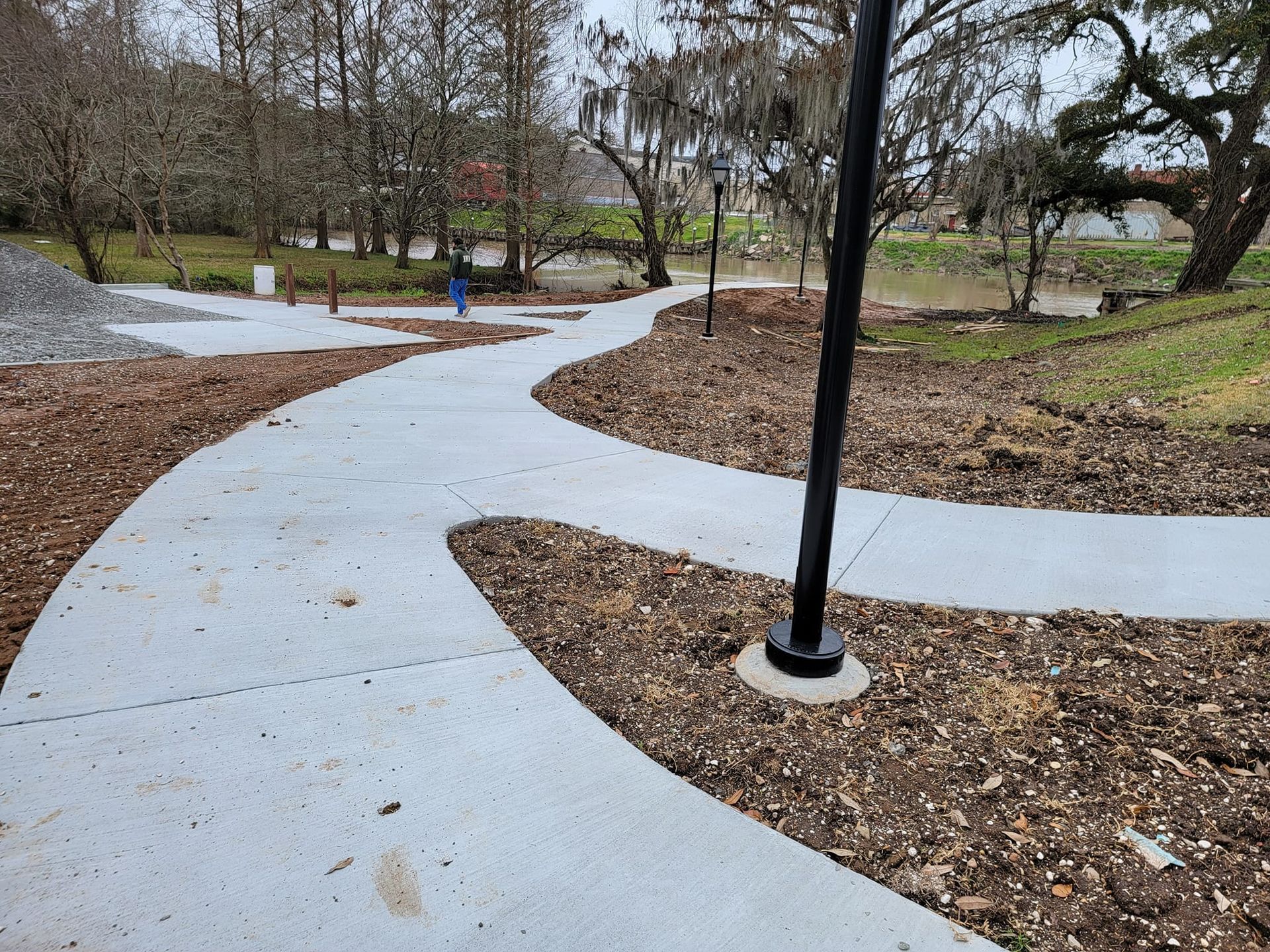 A concrete walkway in a park with trees in the background