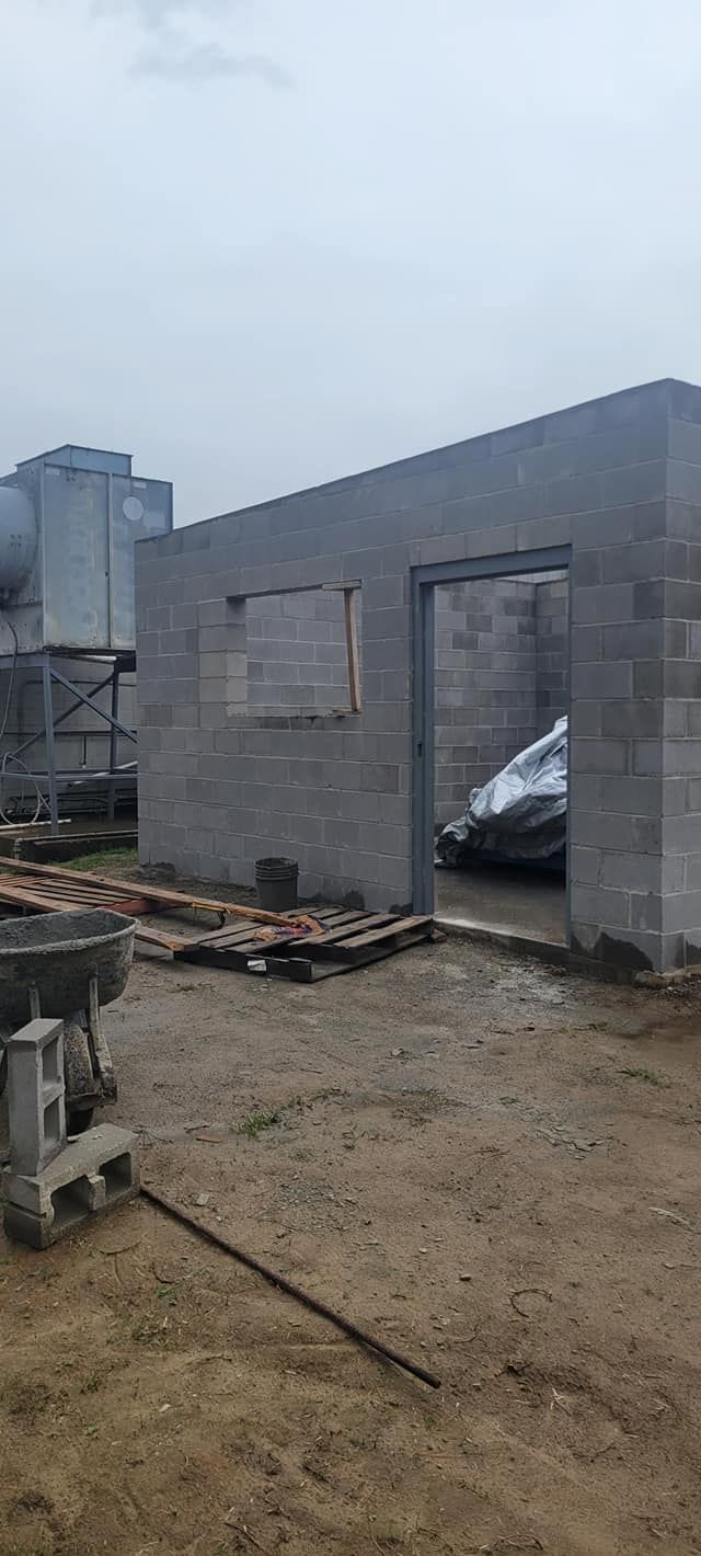 A car is parked in front of a building under construction.