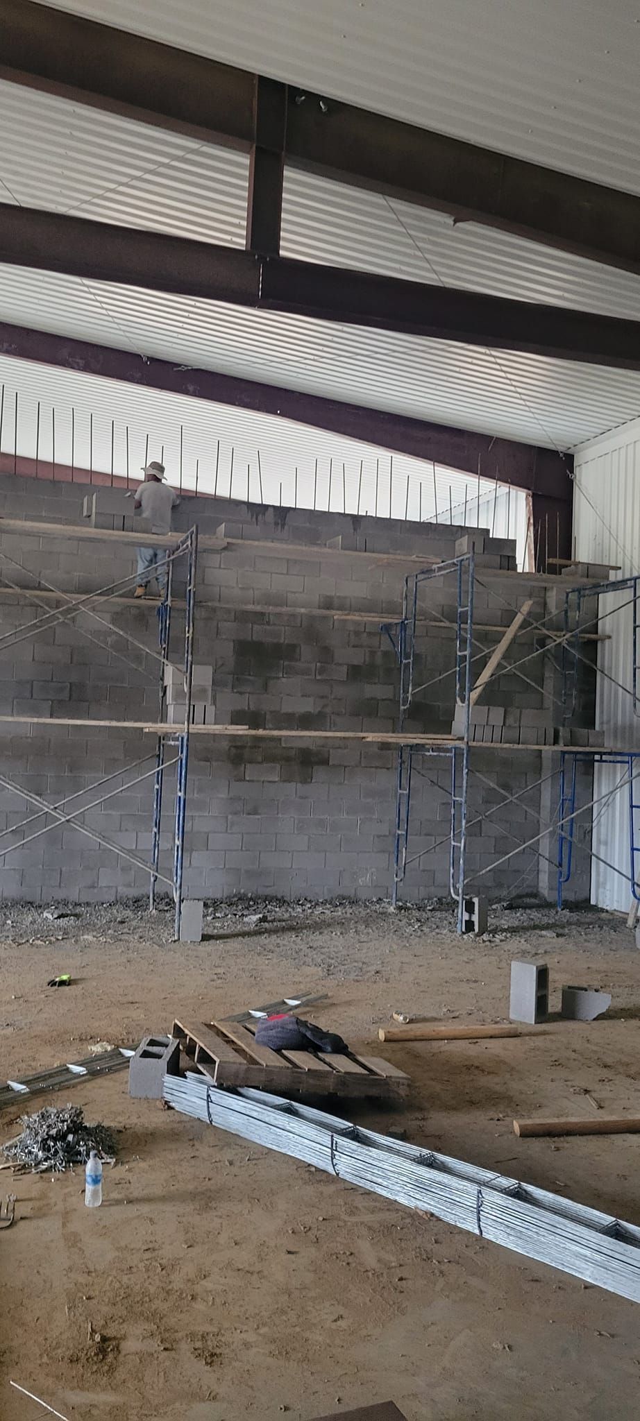 Construction site with tiered concrete structure inside a large building. Scaffolding supports the structure.