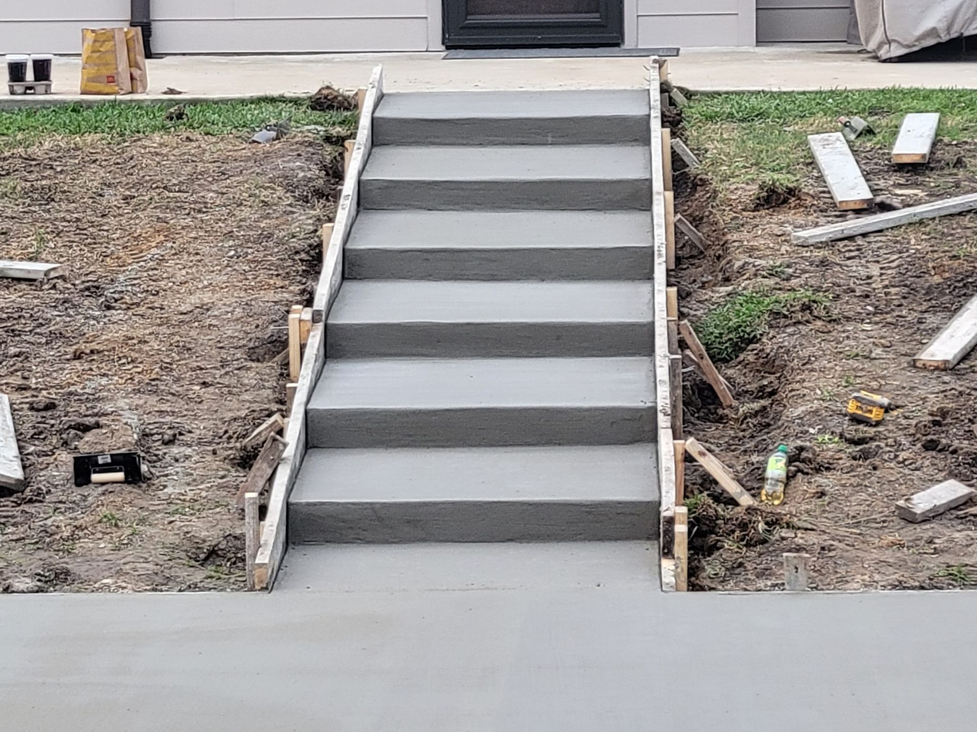 A set of concrete stairs being built in front of a house.